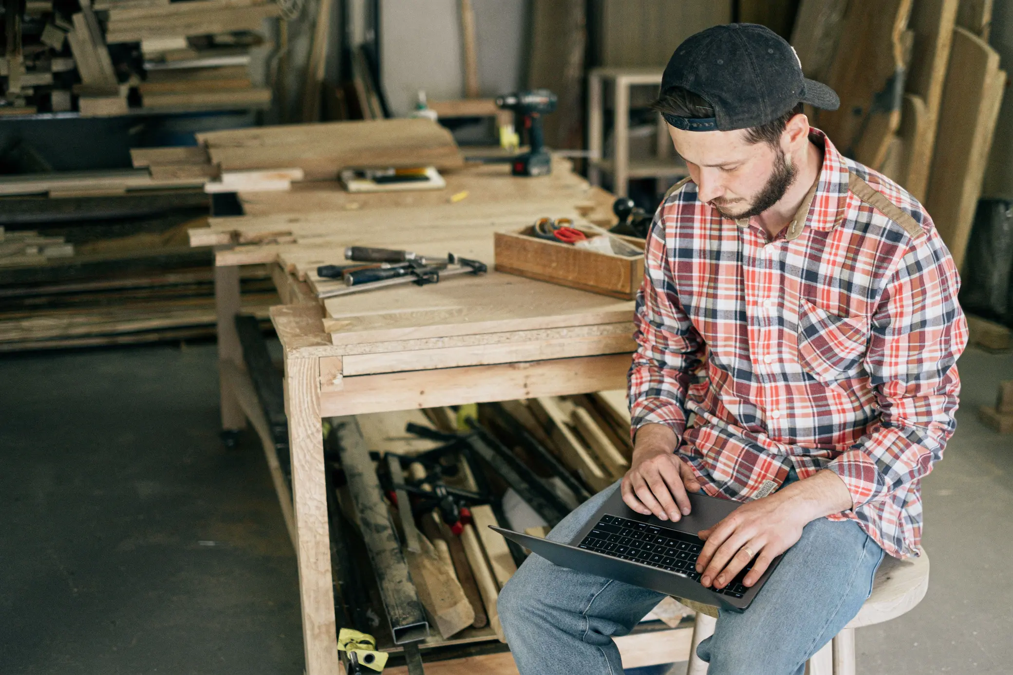 A workshop owner using a laptop beside the workbench